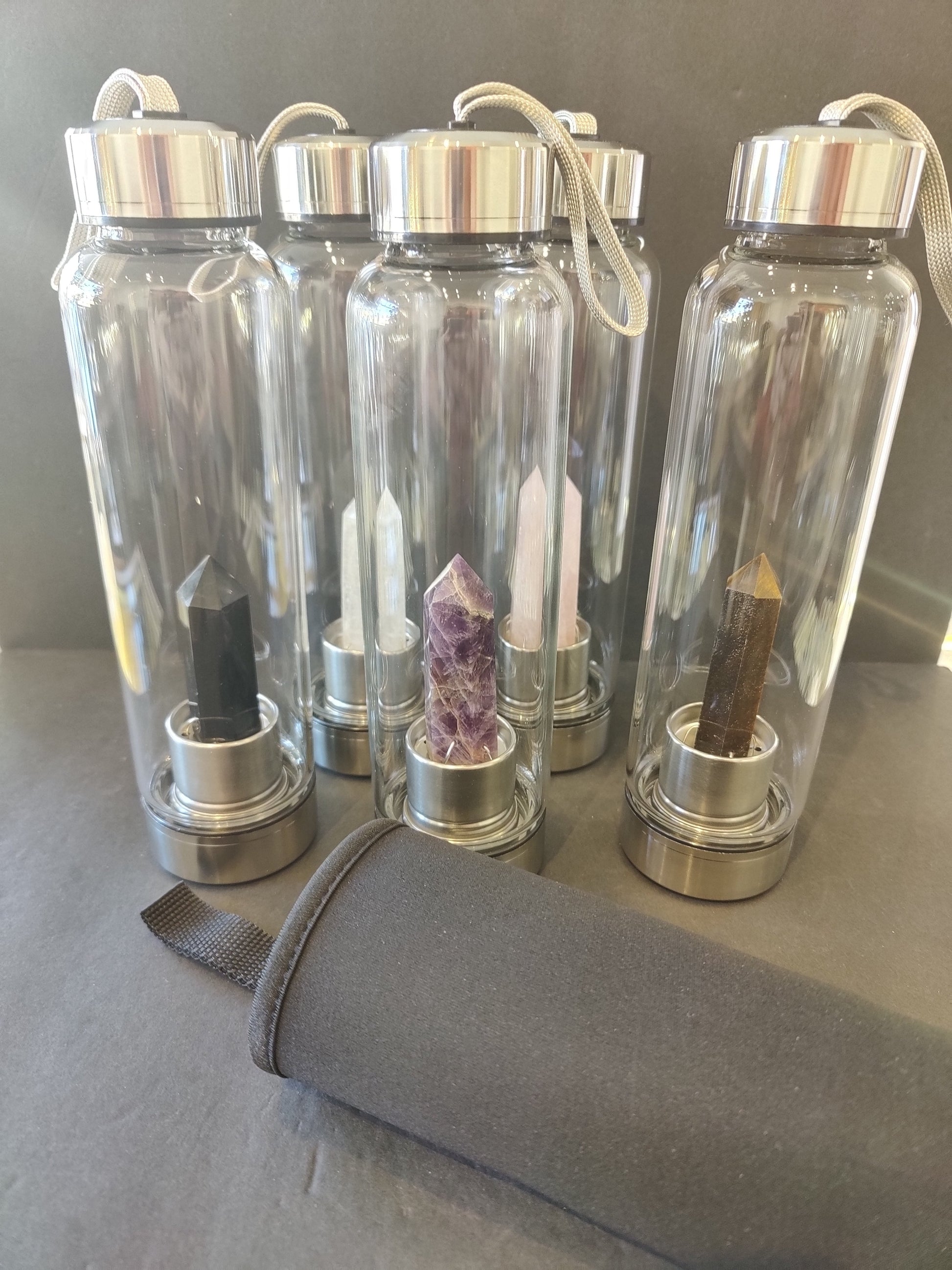Sixteen-ounce crystal infused water bottle in stainless steel and glass with a fabric insulation sleeve and a crystal chamber in the base