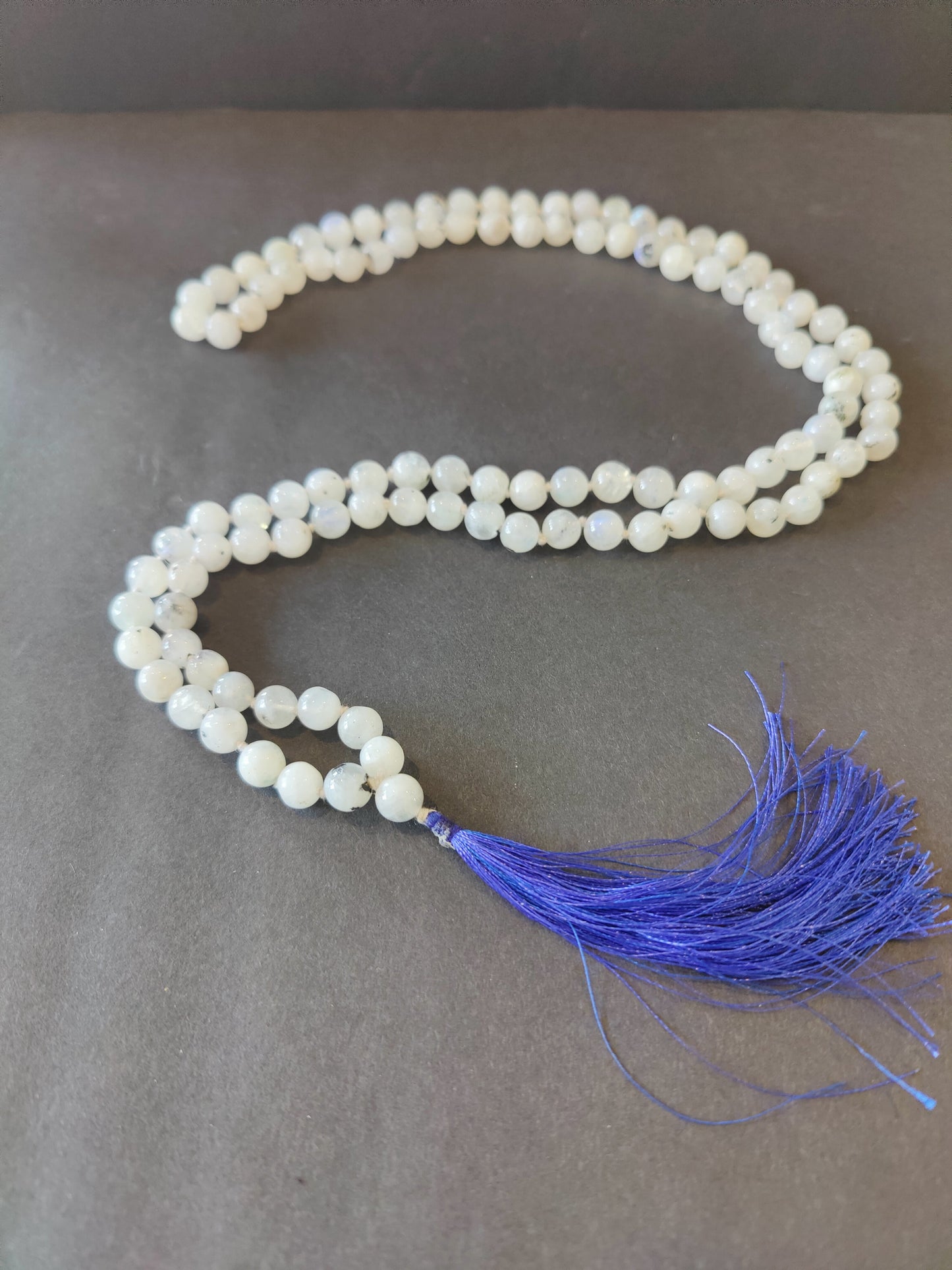 Long mala necklace strung with assorted natural stone beads, hanging in a loop — view 4