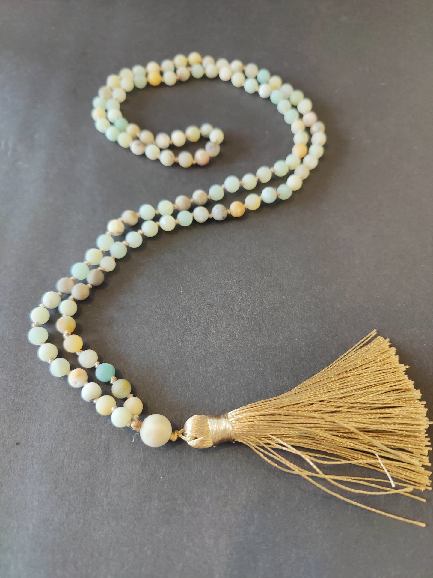 Long mala necklace strung with assorted natural stone beads, hanging in a loop — view 3