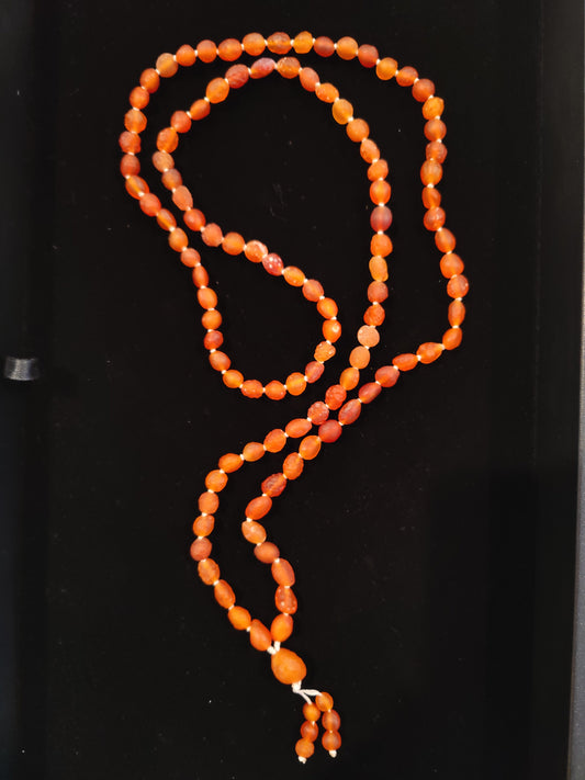 Red carnelian and Gobi Desert agate 108-bead mala necklace, 36 inches long, coiled on a dark surface