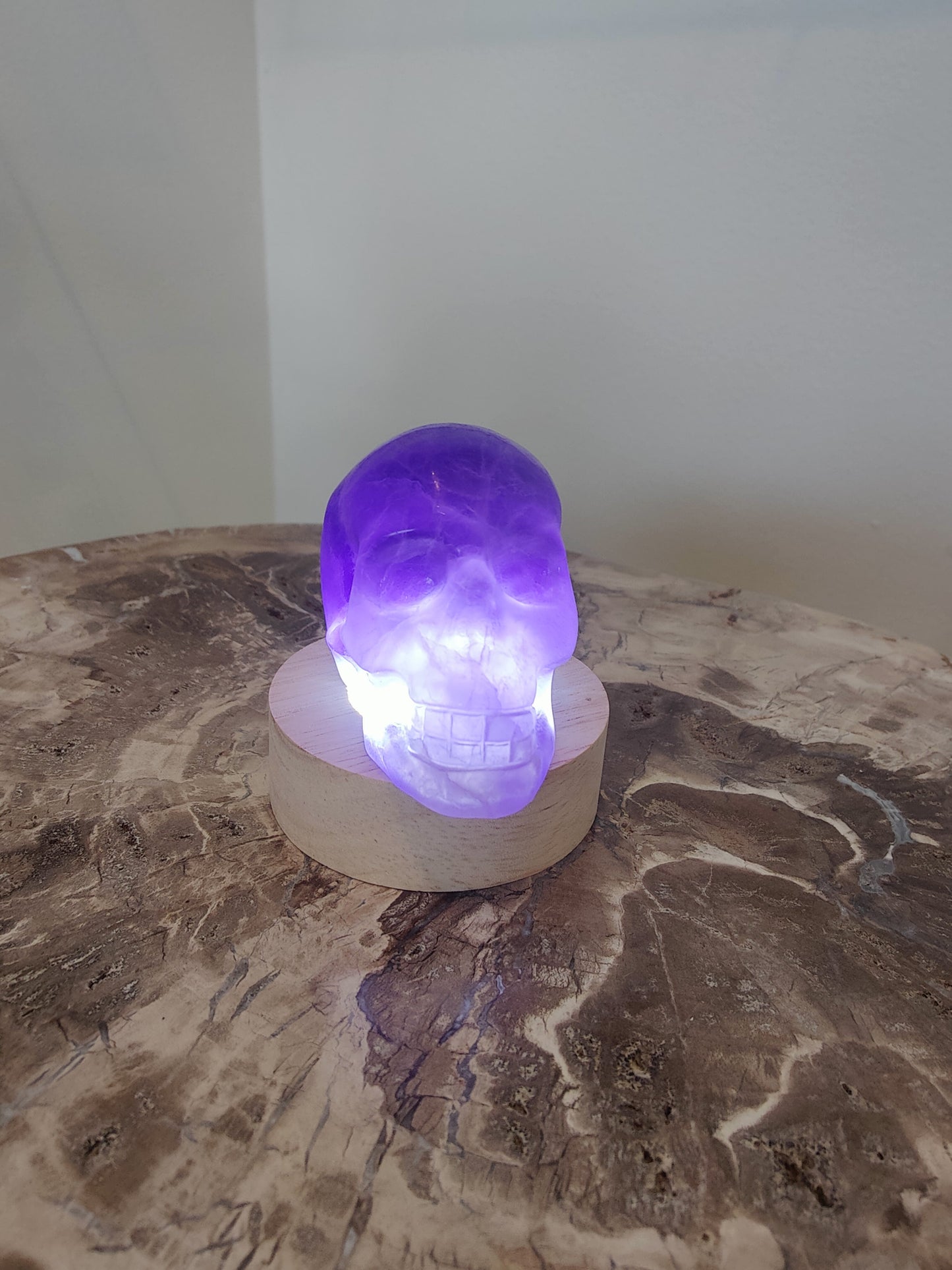 Carved purple fluorite crystal skull with banded violet and clear zones, front three-quarter view — view 4