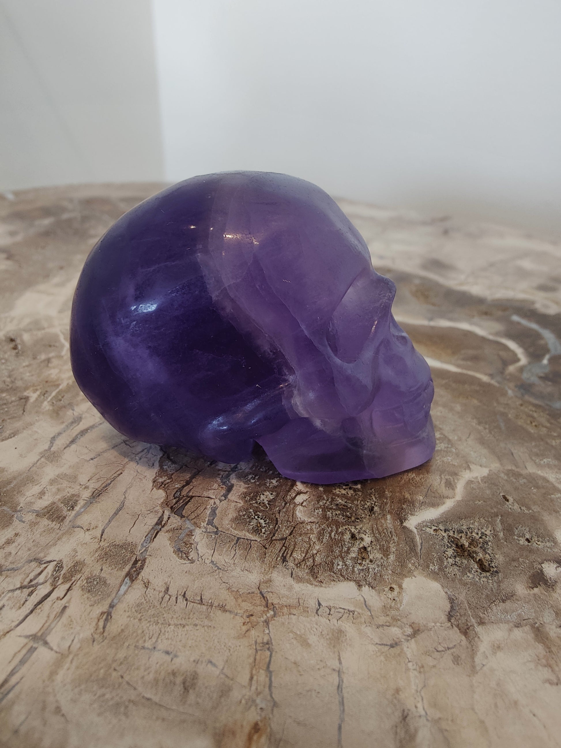 Carved purple fluorite crystal skull with banded violet and clear zones, front three-quarter view — view 3