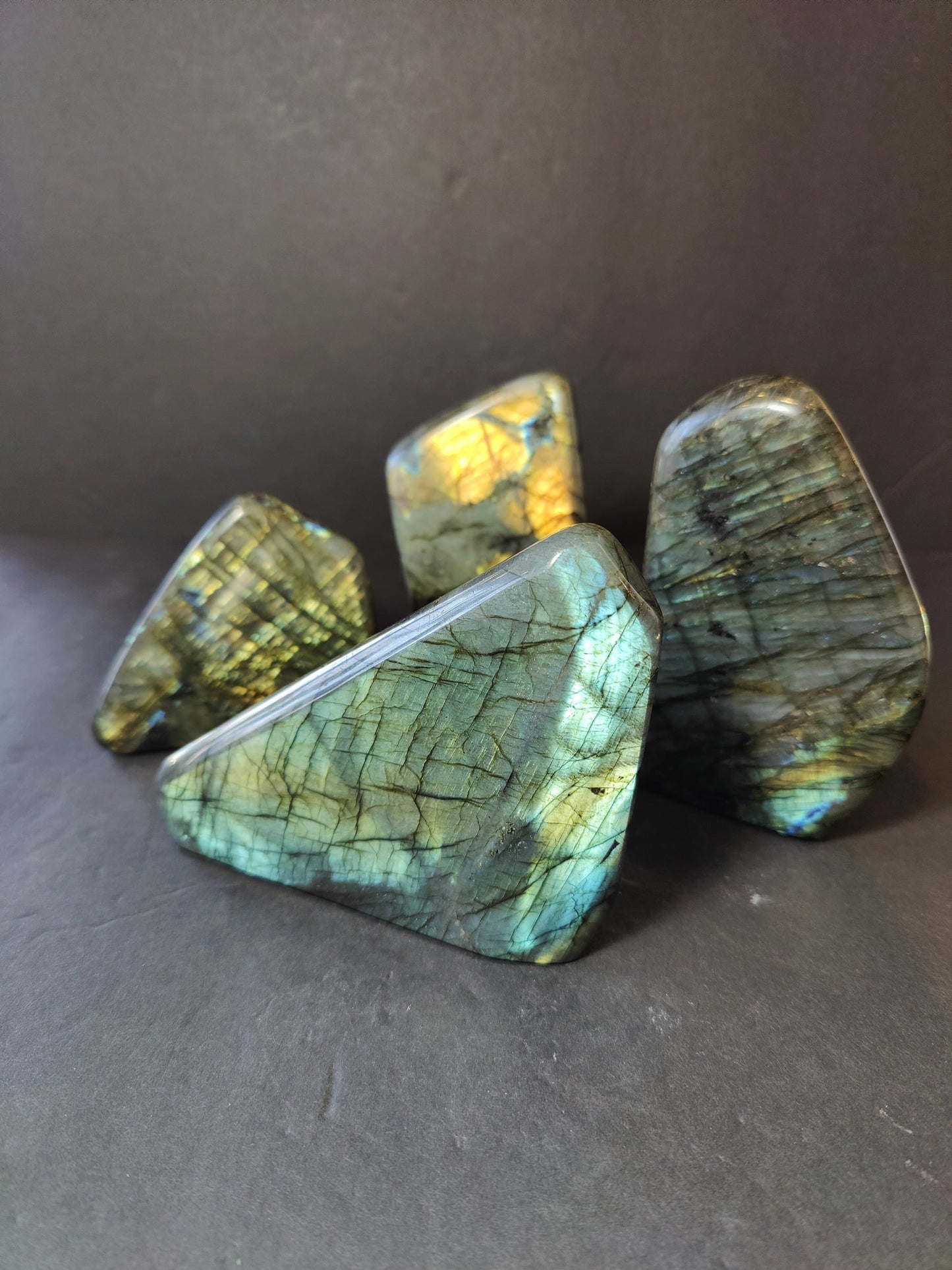 Polished labradorite freeform sculpture from Madagascar showing blue and gold flash across a grey stone surface
