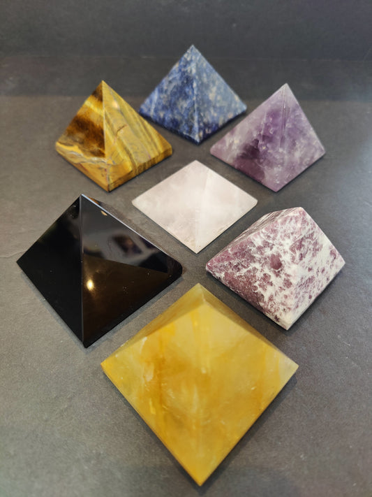 Polished crystal pyramid sculptures in assorted stones including amethyst, tiger eye, black obsidian and rose quartz