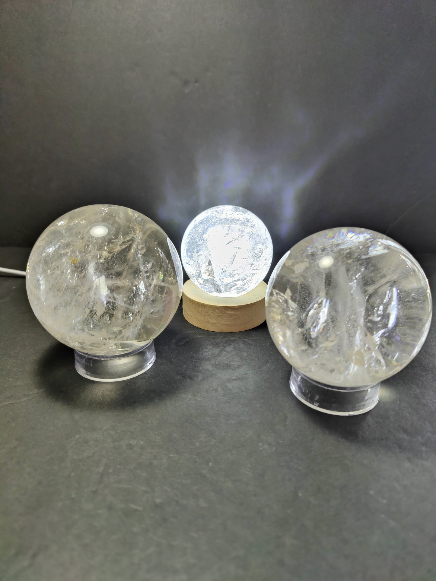 Polished clear quartz crystal sphere catching the light, with natural internal veils