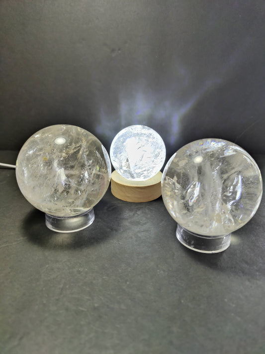 Polished clear quartz crystal sphere catching the light, with natural internal veils