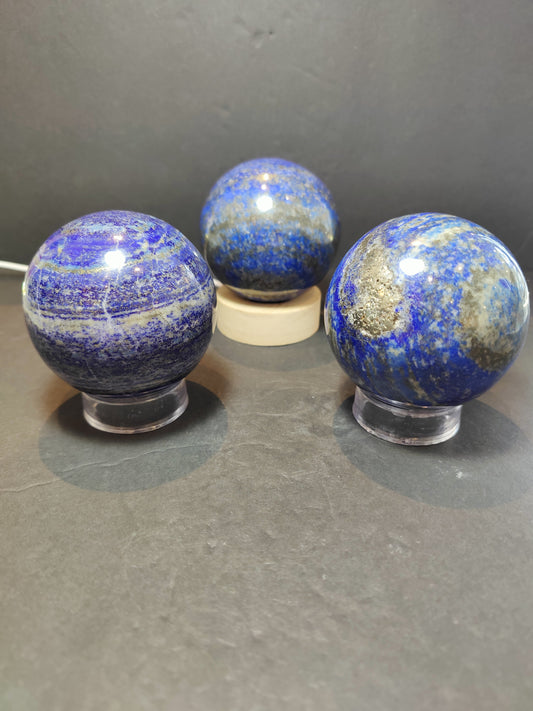 Polished deep blue lapis lazuli sphere with natural golden flecks, 80 millimetres across