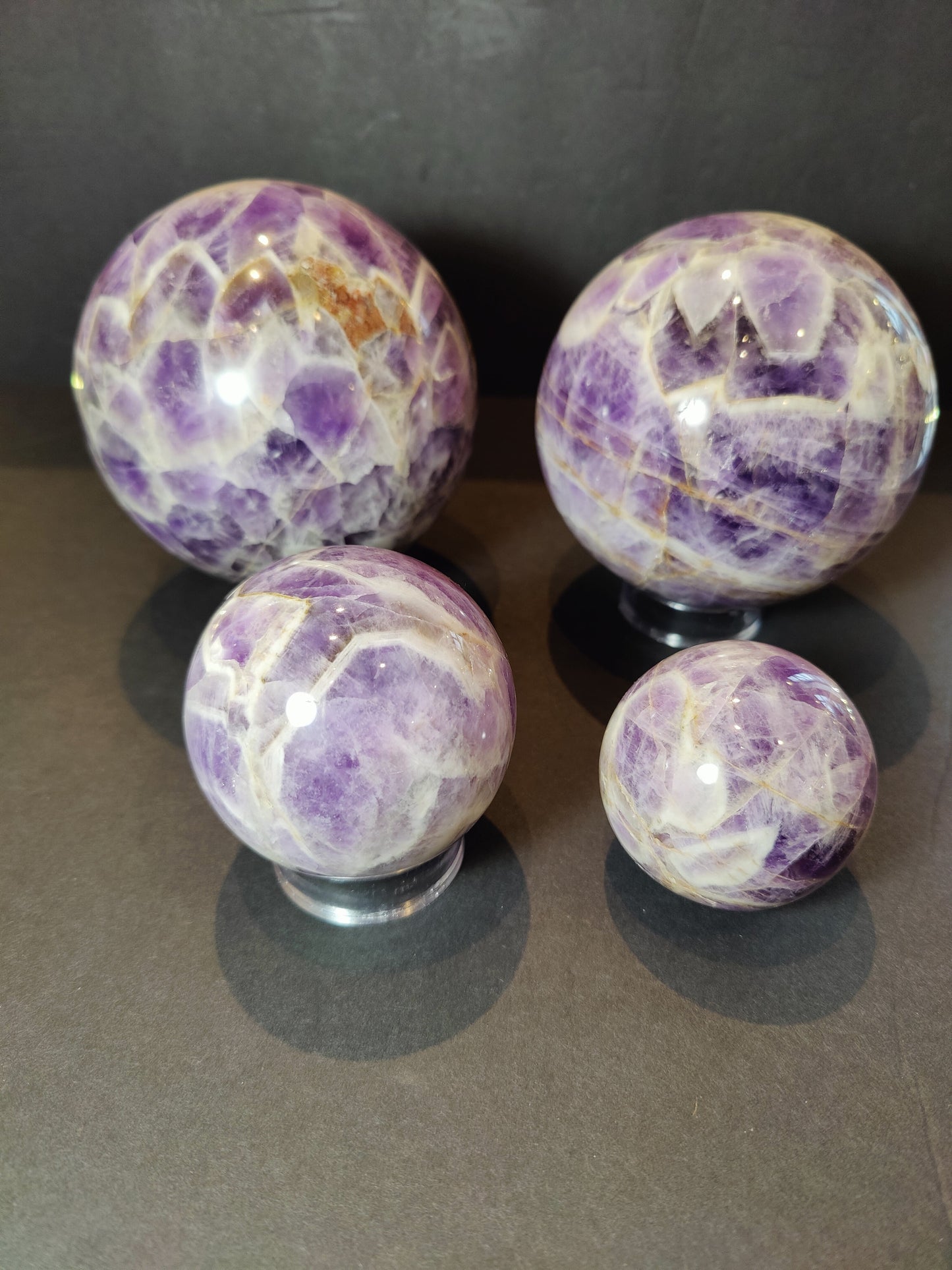 Polished chevron amethyst sphere with V-shaped bands of purple and white quartz