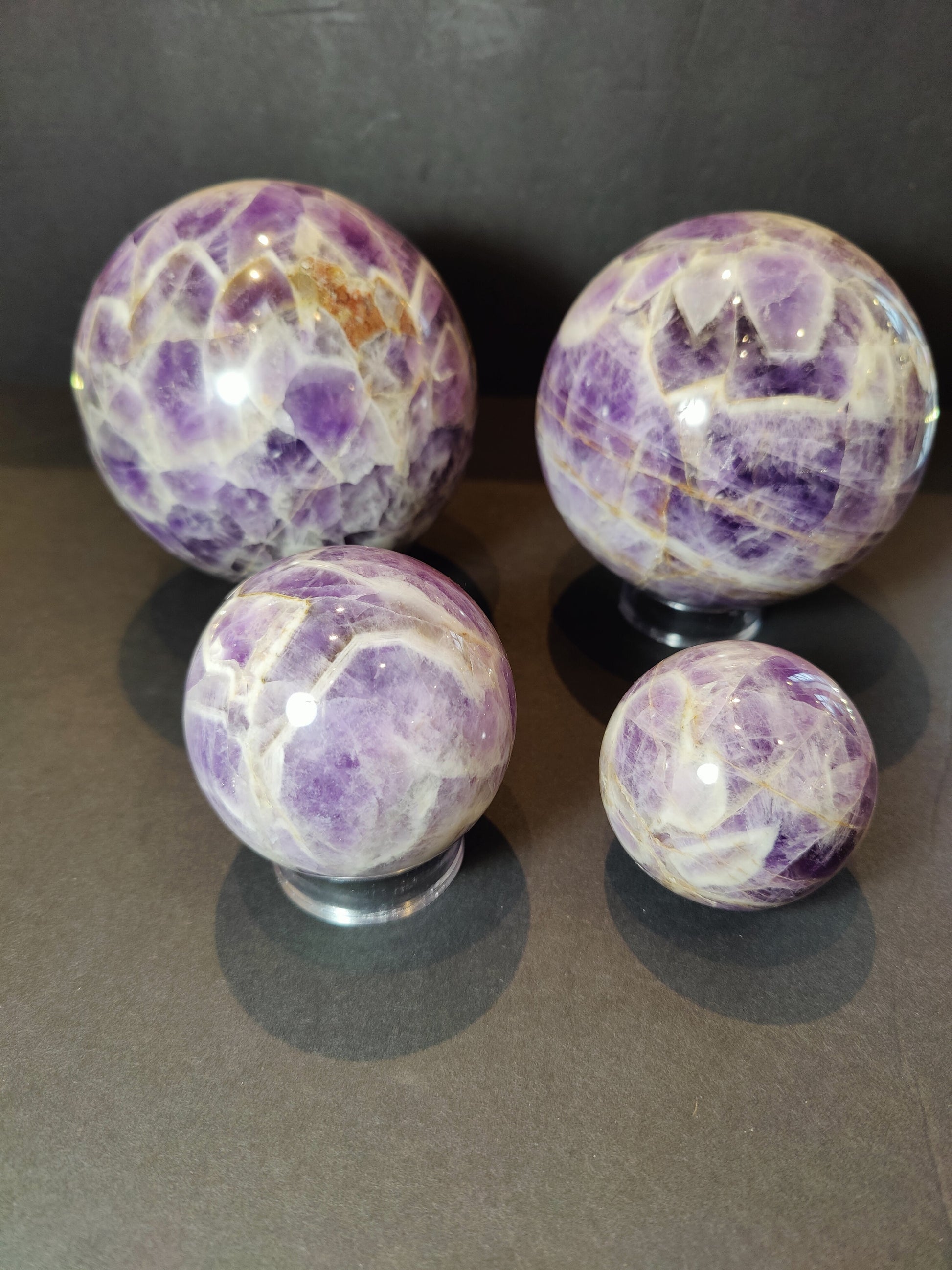 Polished chevron amethyst sphere with V-shaped bands of purple and white quartz