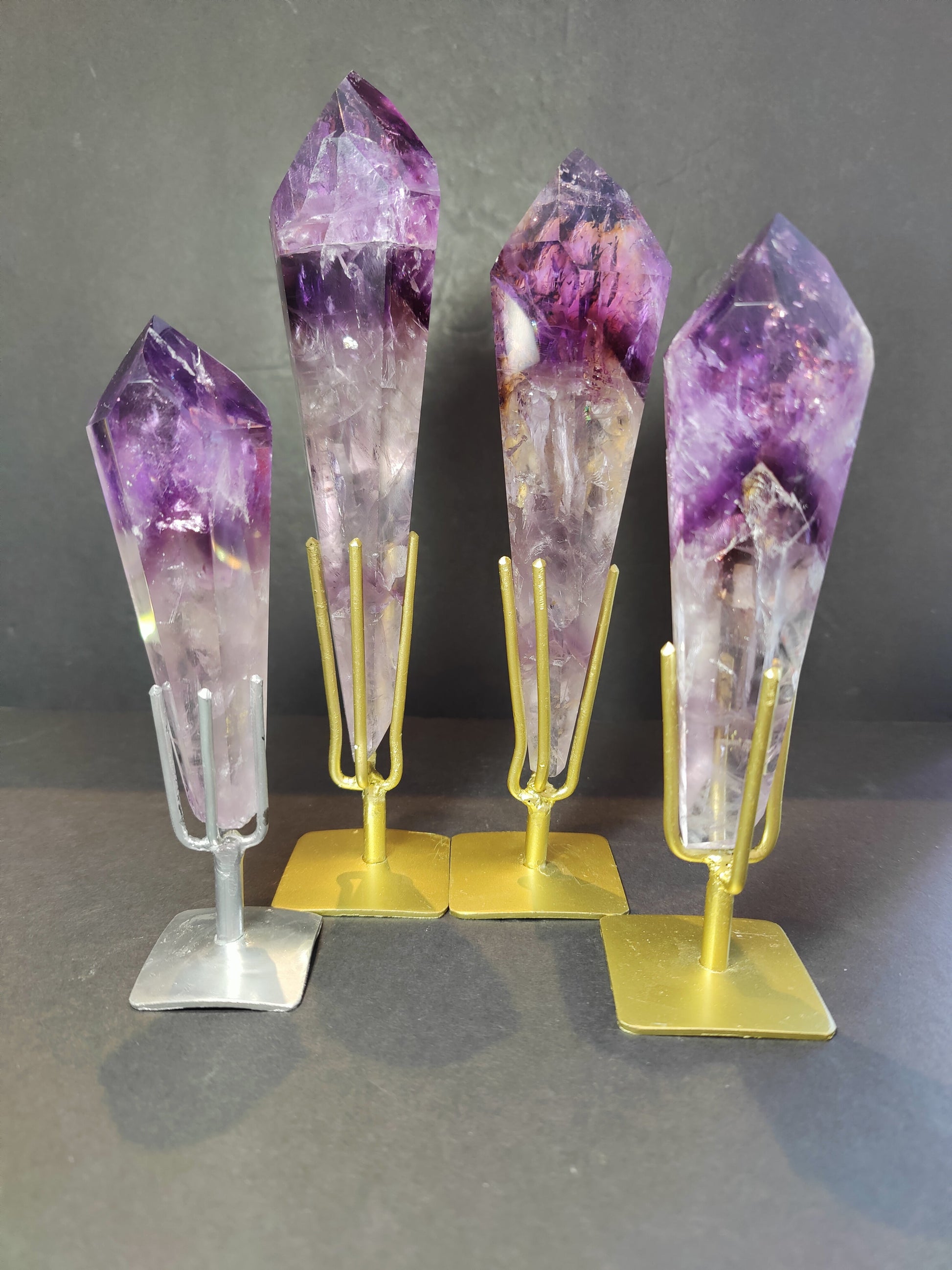 Polished amethyst scepter wand upright on its metal display stand