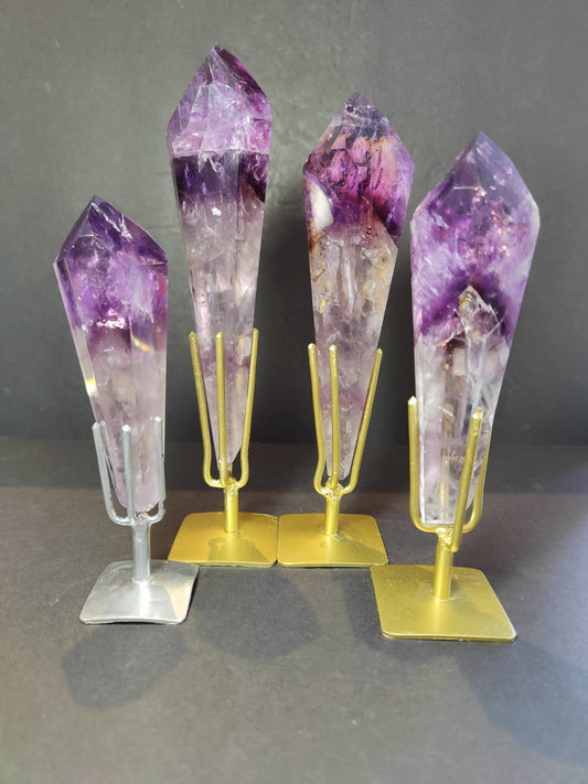 Polished amethyst scepter wand upright on its metal display stand