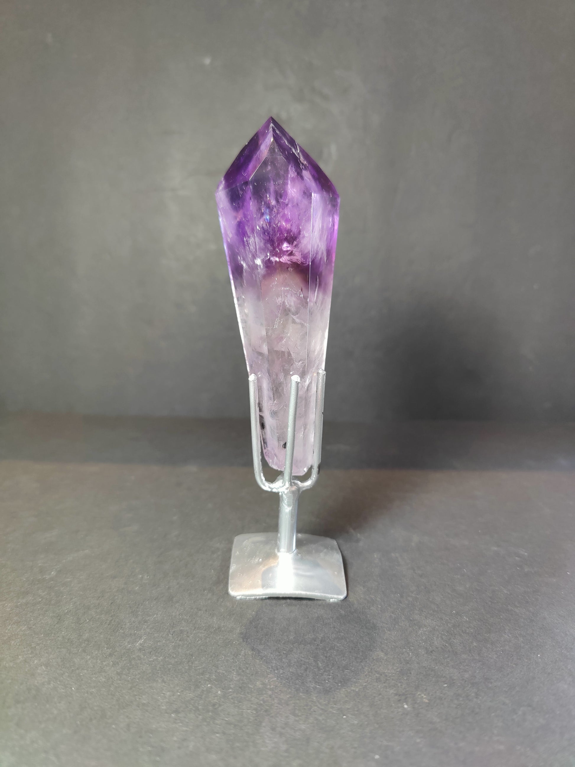 Amethyst scepter wand upright on a metal stand, deep purple head above a paler stem