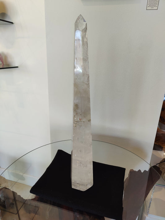 Tall polished clear quartz obelisk standing 20.5 inches, with natural internal veils