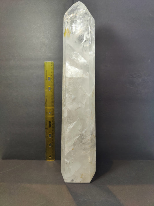 Polished clear quartz obelisk standing upright against a dark background