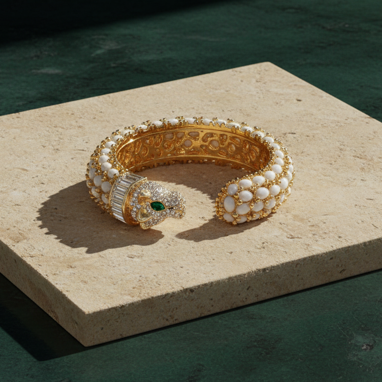 White panther cuff on a pale stone slab, rows of white oval cabochons with gold beading and a pavé-set panther head.