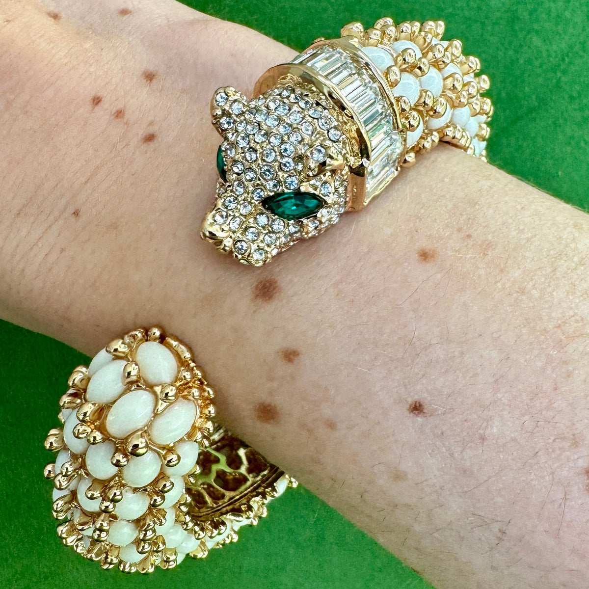 The white panther cuff worn on a wrist, the pavé head with green marquise eyes facing the rounded tail.