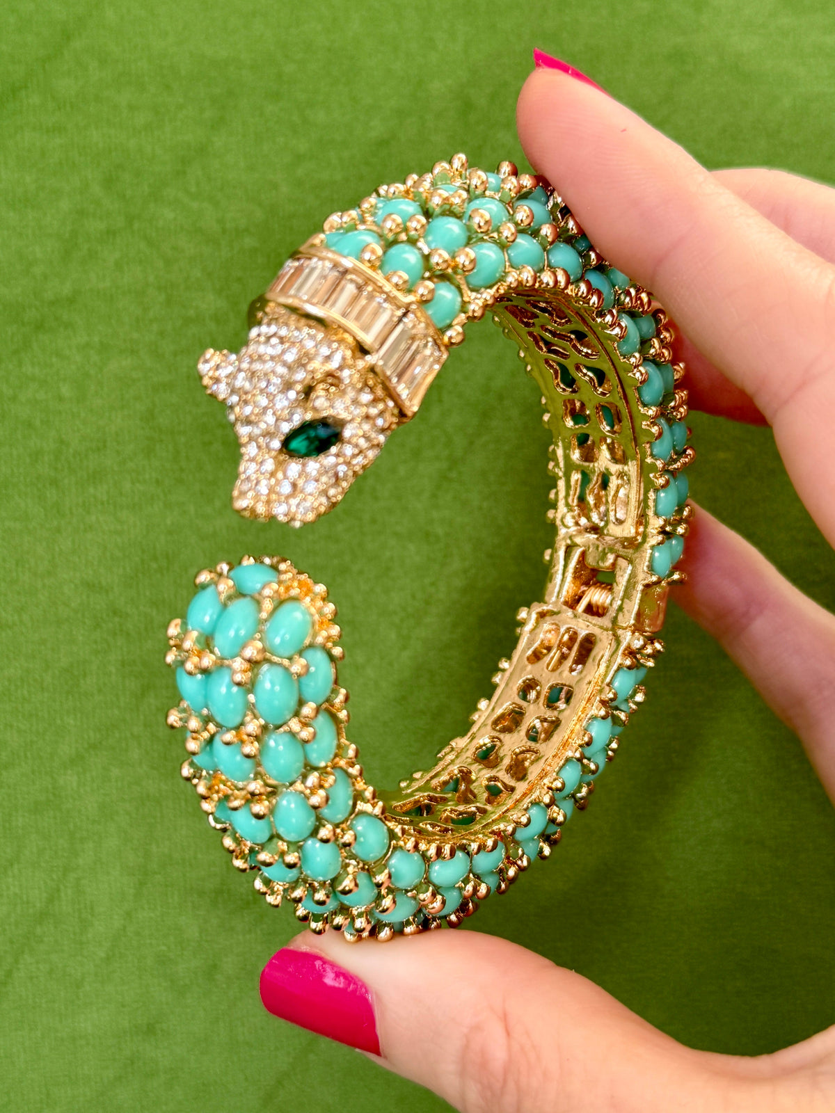 The open turquoise cuff held in a hand, showing the pierced gold gallery inside the shank.