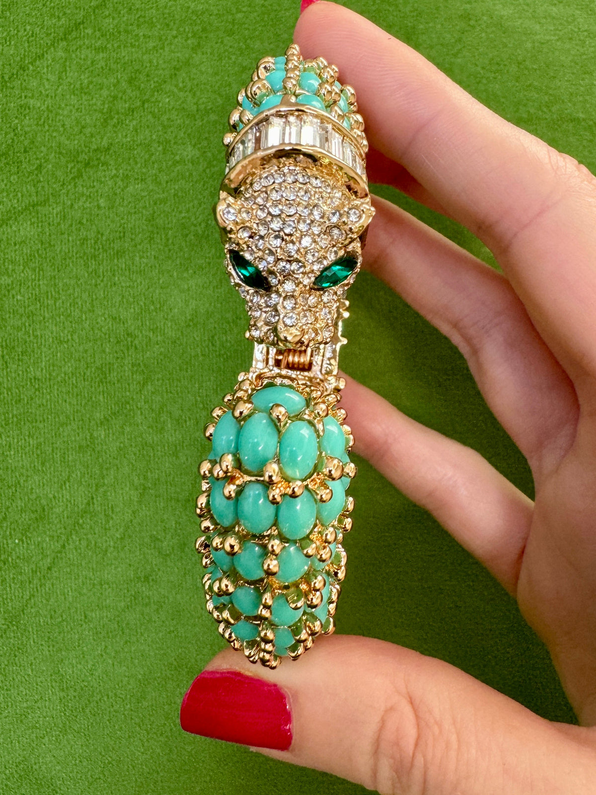Head-on view of the turquoise panther cuff, the pavé face with green marquise eyes above the turquoise cabochon tail.
