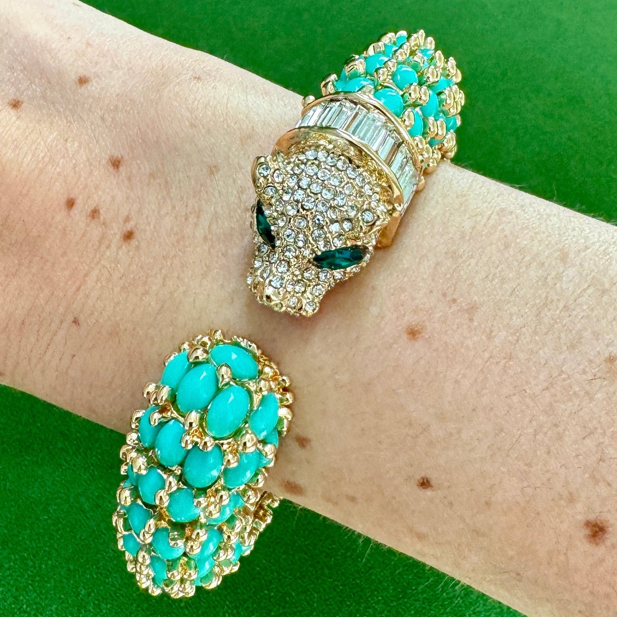 The turquoise panther cuff worn on a wrist, the pavé head with a green marquise eye facing the rounded tail.