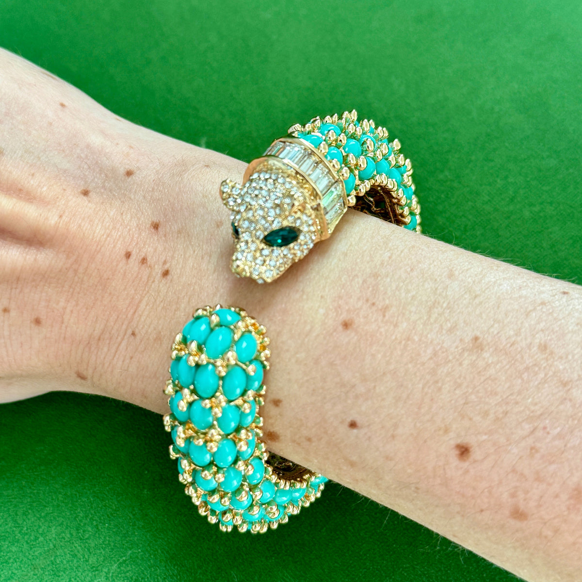 The turquoise panther cuff worn on a wrist seen from above, both ends of the open shank visible.