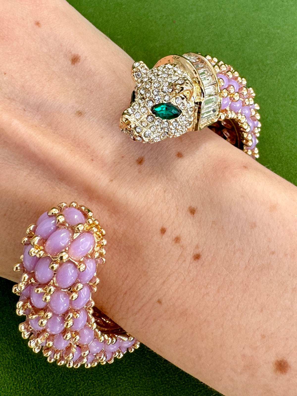 The lavender panther cuff worn on a wrist, the pavé head with a green marquise eye facing the rounded tail end.