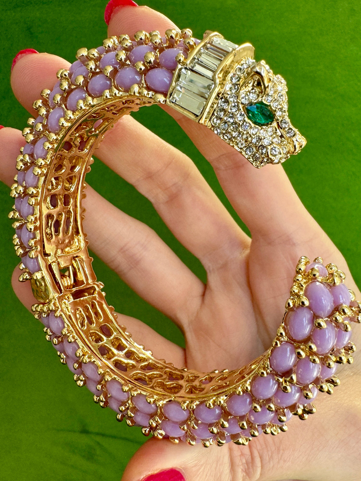 The open lavender cuff resting in a palm, lavender cabochons and gold beading covering the outer face.