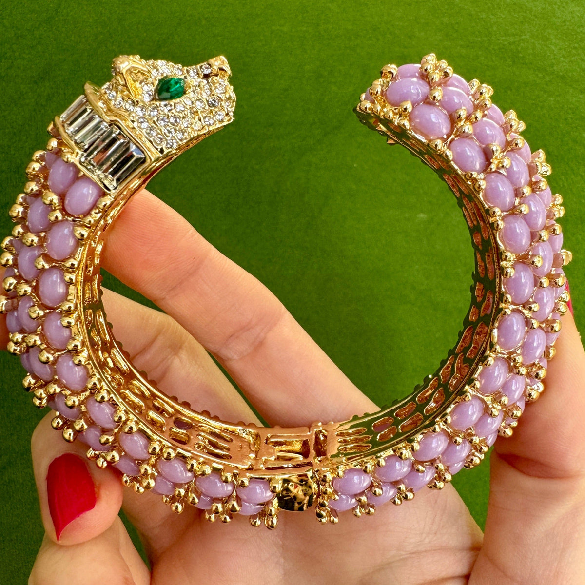 The lavender panther cuff held open in a hand, showing the pierced gold gallery running along the inside of the shank.