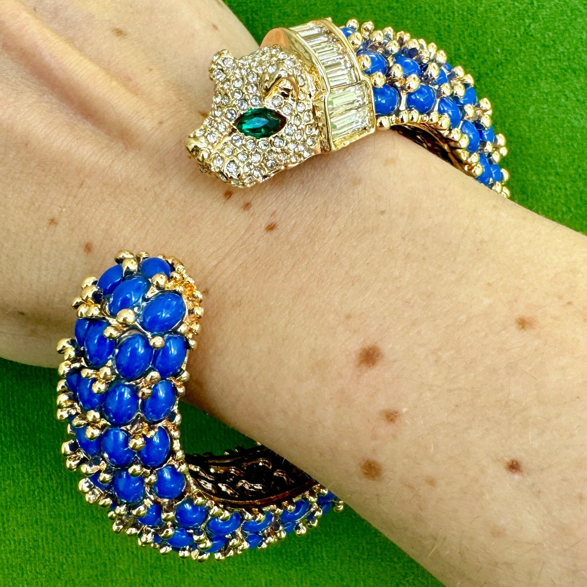 The navy blue panther cuff worn on a wrist, the pavé head with a green marquise eye facing the rounded tail.