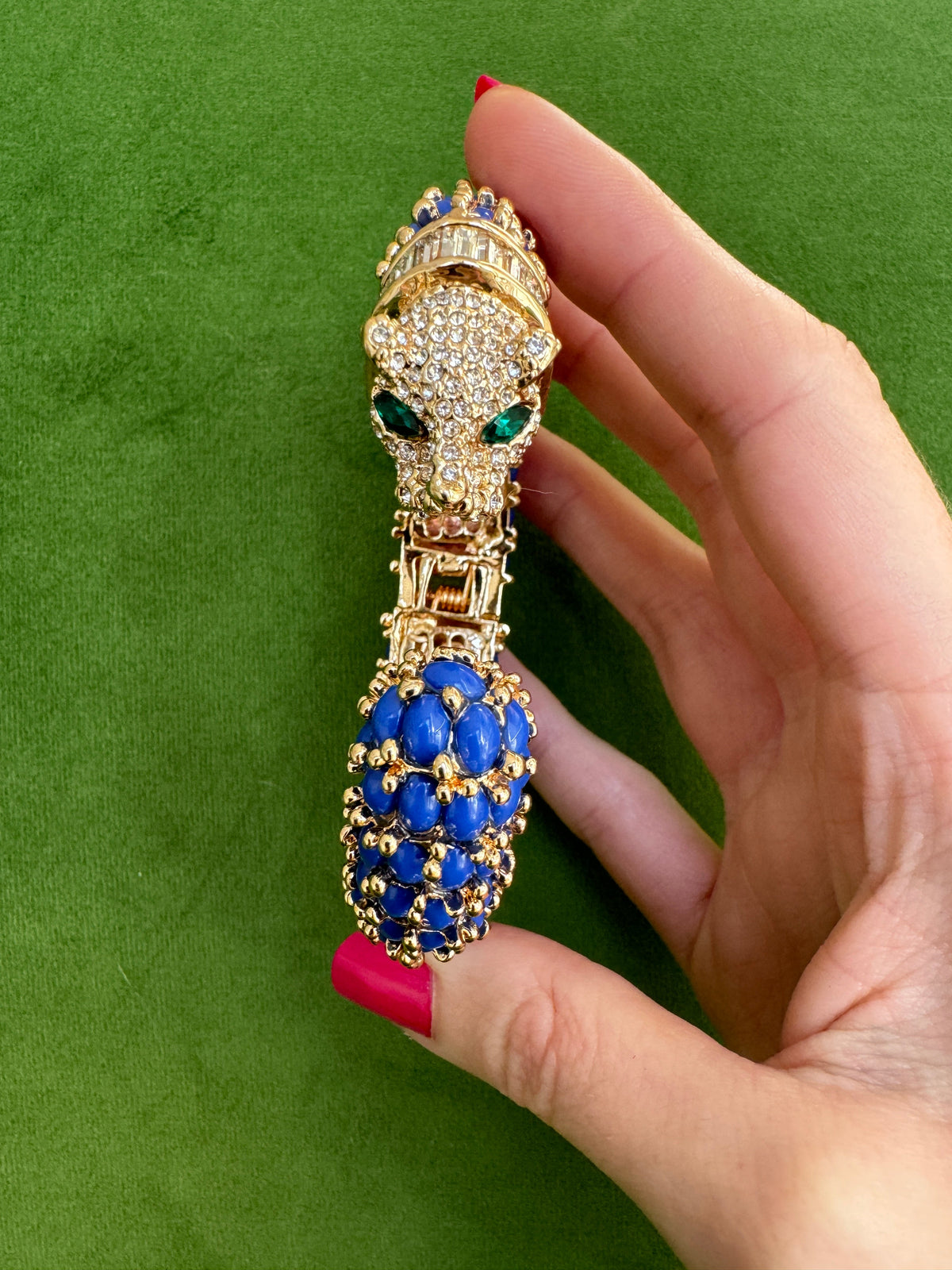 Head-on view of the navy blue panther cuff, the pavé face with green marquise eyes above the blue cabochon tail.