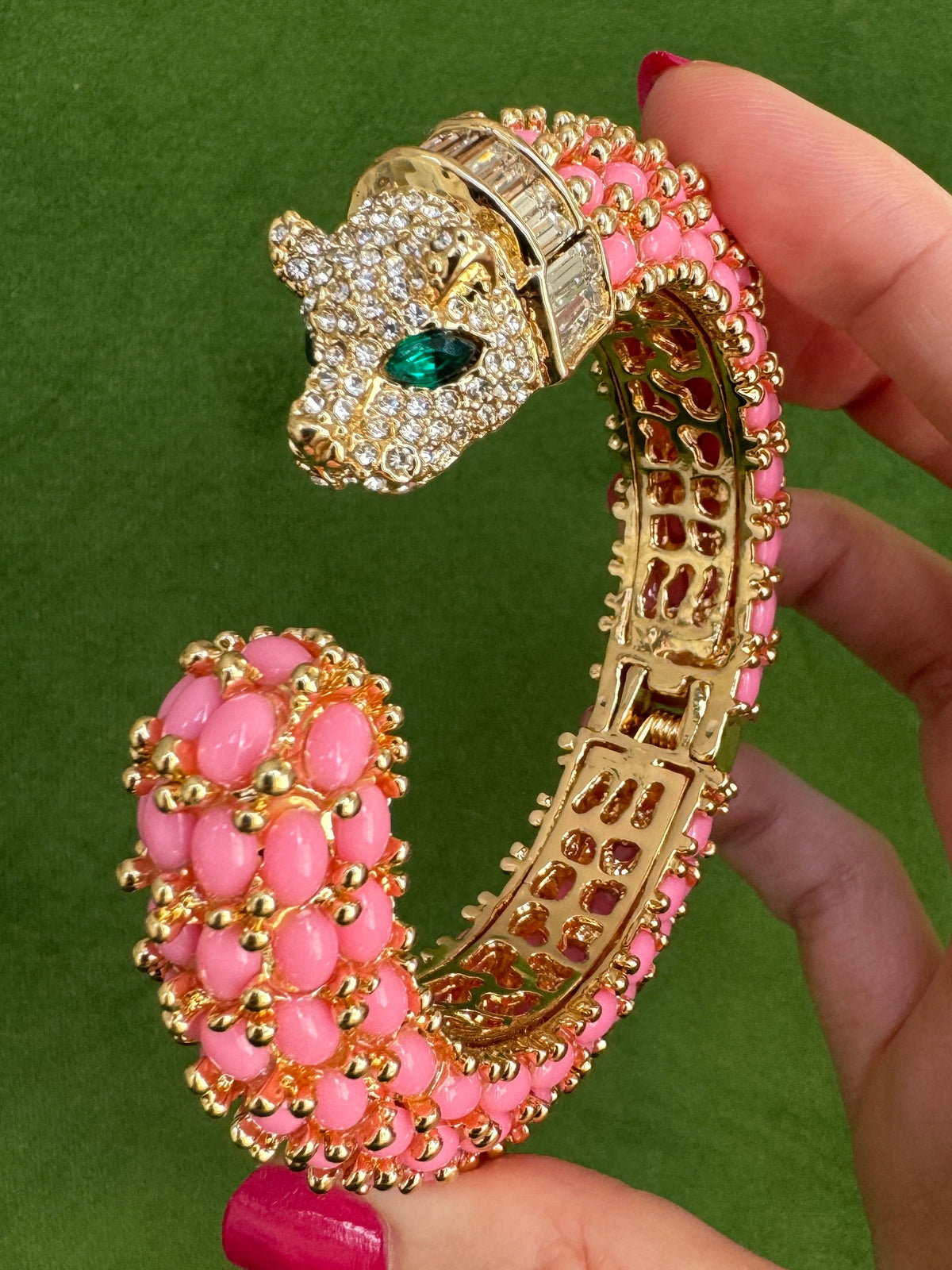 The bright pink panther cuff seen from the side, the baguette-set collar sitting behind the pavé head.