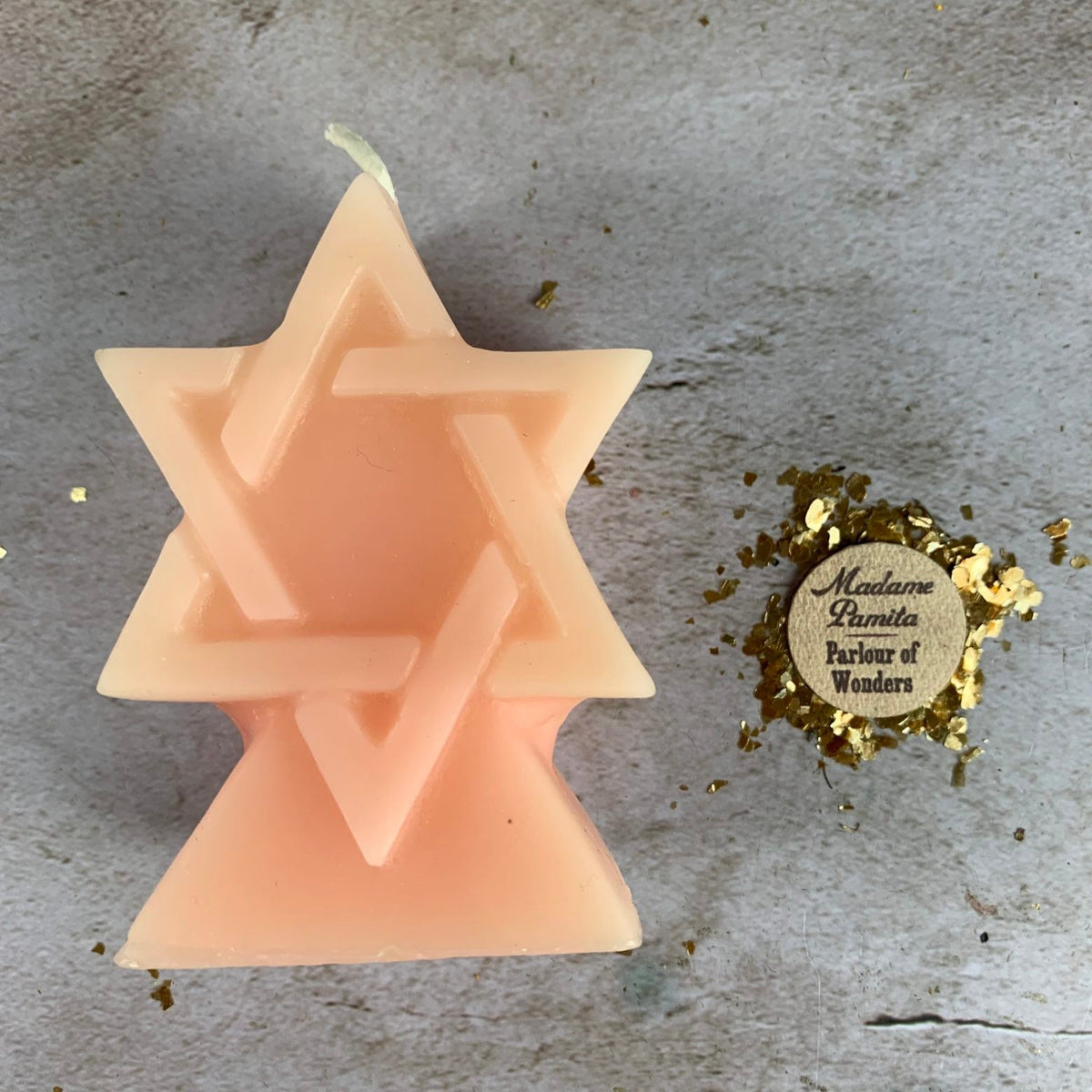 Blush pink beeswax Seal of Solomon hexagram candle photographed from above on stone