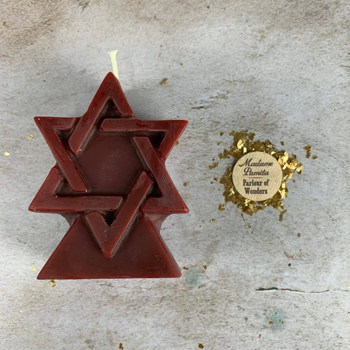 Deep maroon red beeswax Seal of Solomon hexagram candle on a pale stone surface
