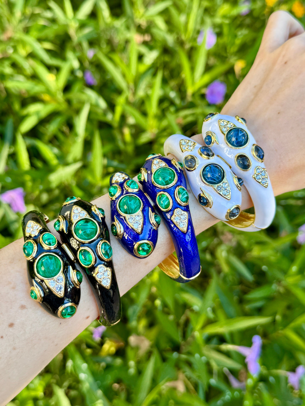 Four colorways of the snake bracelet worn together on one arm — black with green, blue with green, and the white with blue sold here on the right.
