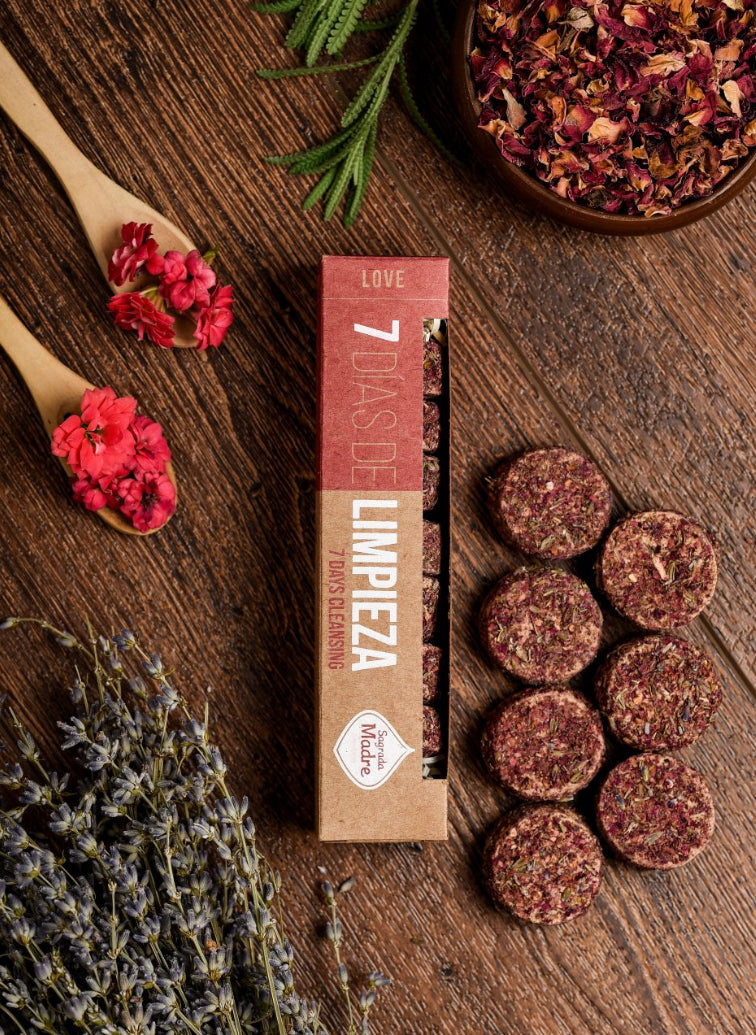 Seven-day charcoal tablet box with rose-red herb-topped discs and dried petals