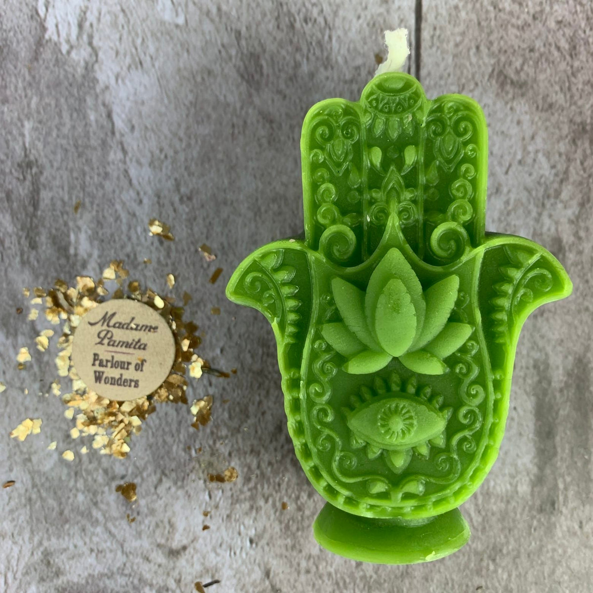 Green Hamsa candle, lotus centered above an open eye, standing on its small molded foot.