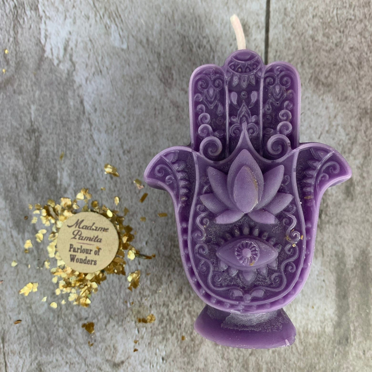 Purple Hamsa candle with a lightly mottled surface where the wax cooled.