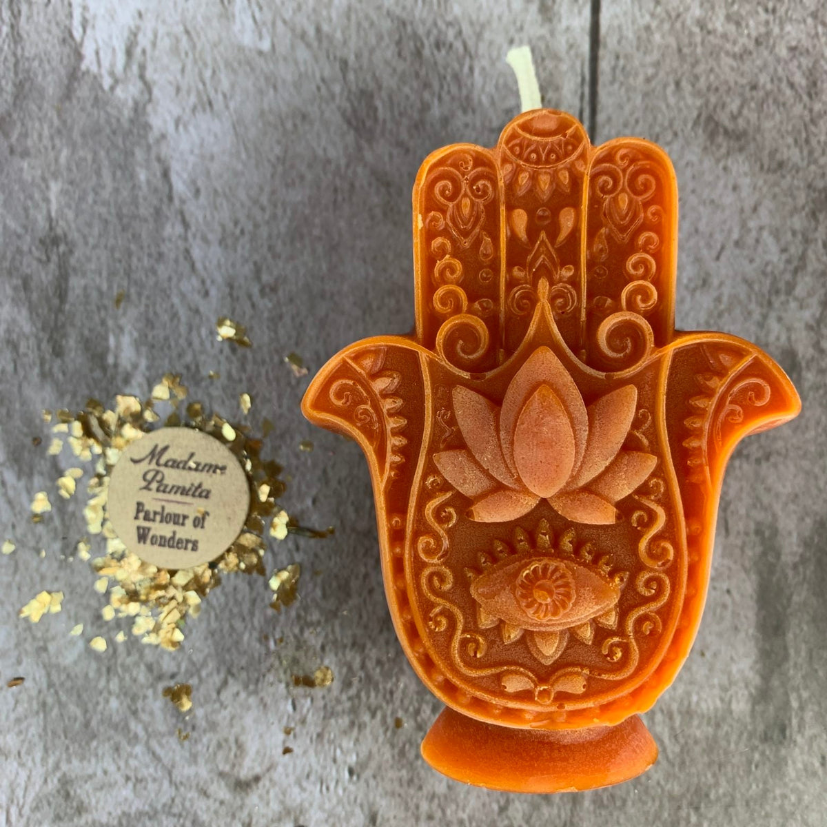 Orange Hamsa candle, the filigree and lotus catching the light.
