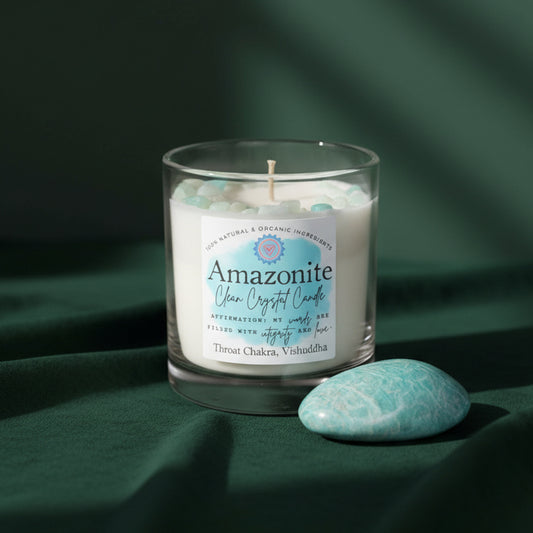 Amazonite Clean Crystal Candle, label reading Throat Chakra Vishuddha, on dark green fabric beside a polished blue-green amazonite palm stone.