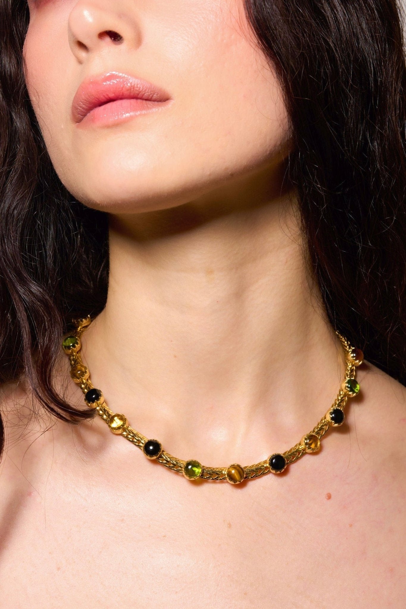 A woven gold chainmail choker set with genuine black onyx, tiger eye and peridot stones, shown from a different angle.