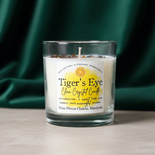 Tiger's Eye Clean Crystal Candle labeled Solar Plexus Chakra Manipura, on a pale ledge against a dark green backdrop.