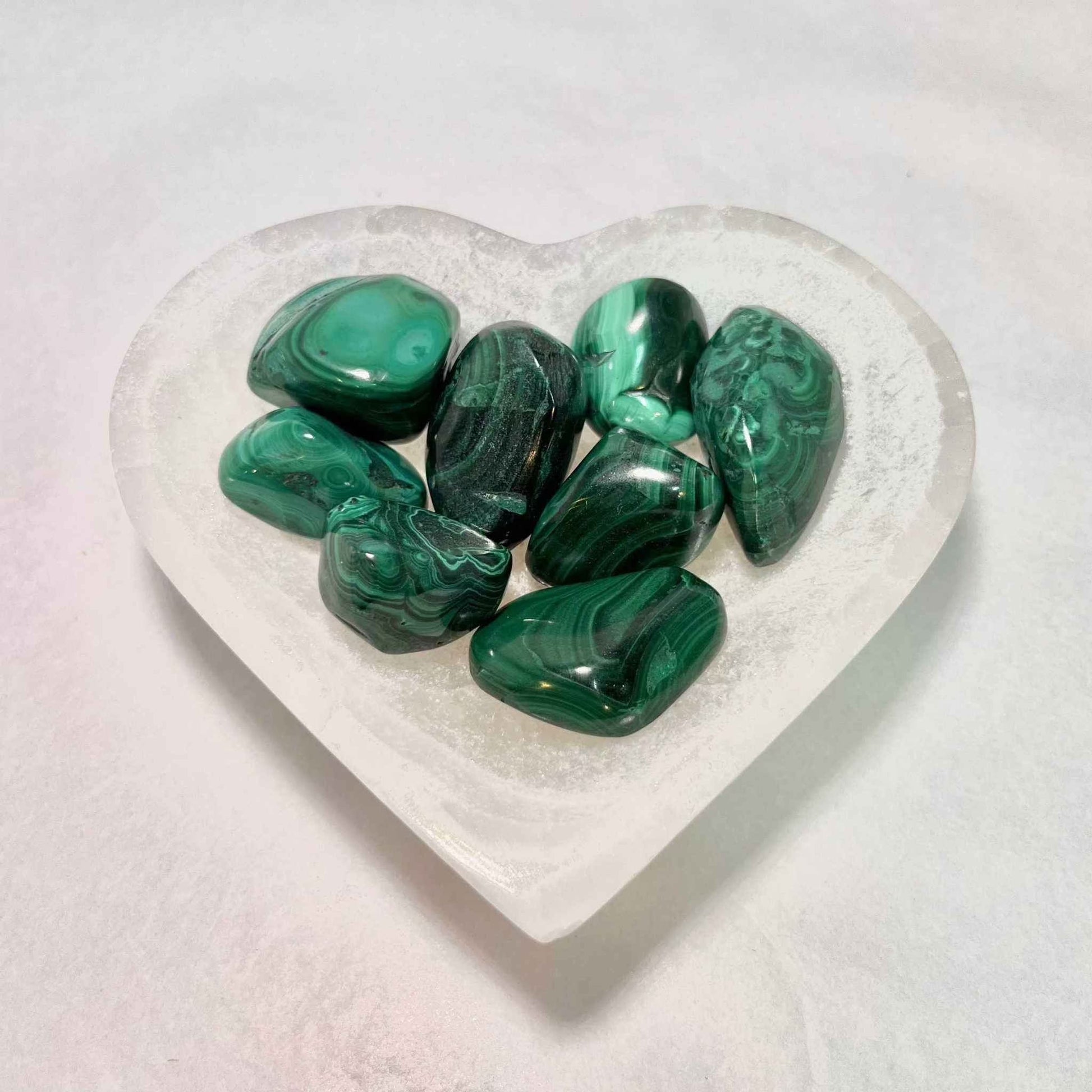 Malachite tumbled stone held to show its palm-friendly size