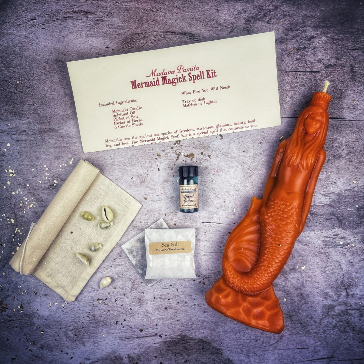 Burnt-orange mermaid candle with the kit laid out on gray stone.