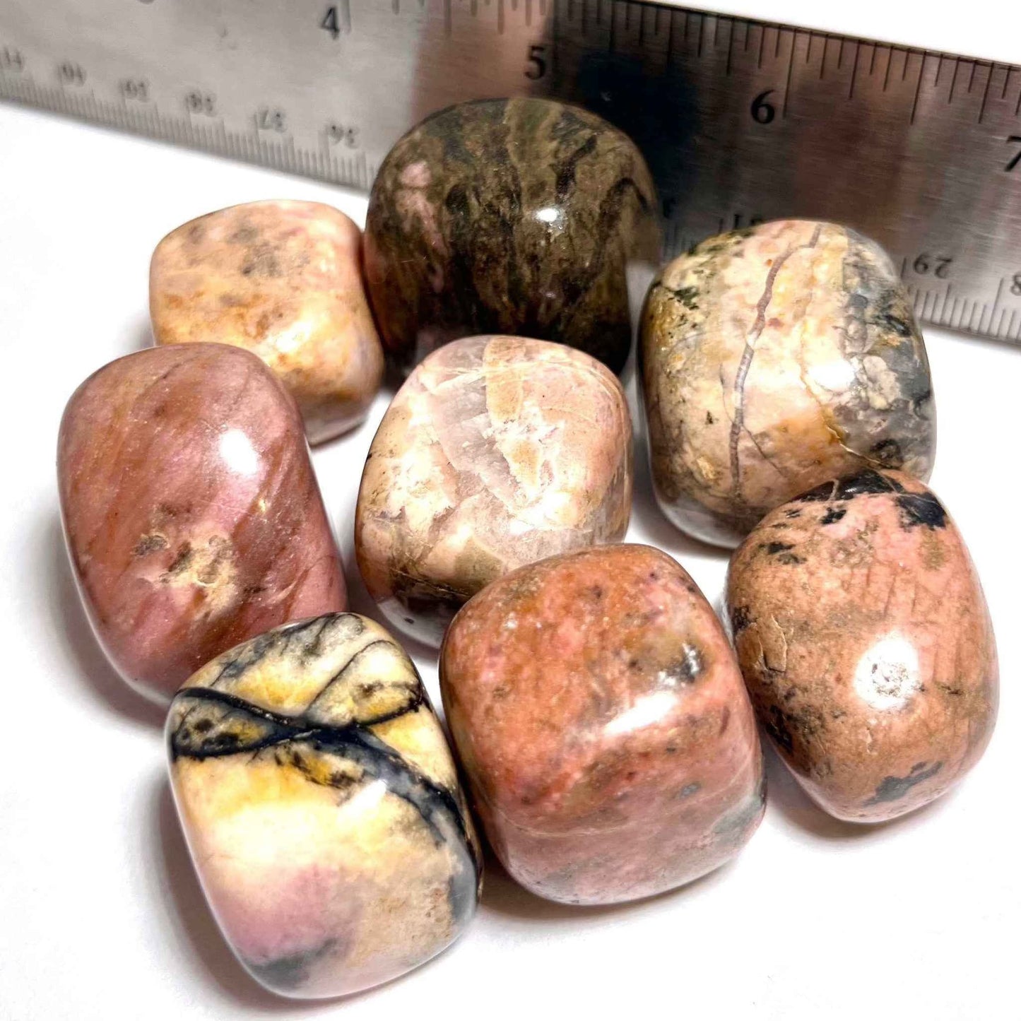 A rhodonite pocket stone shown from another angle, its pink surface polished smooth.
