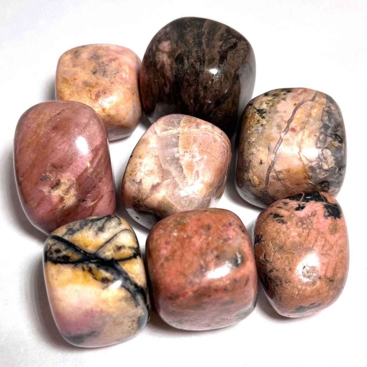 A tumbled rhodonite pocket stone in soft pink marked with black veining.