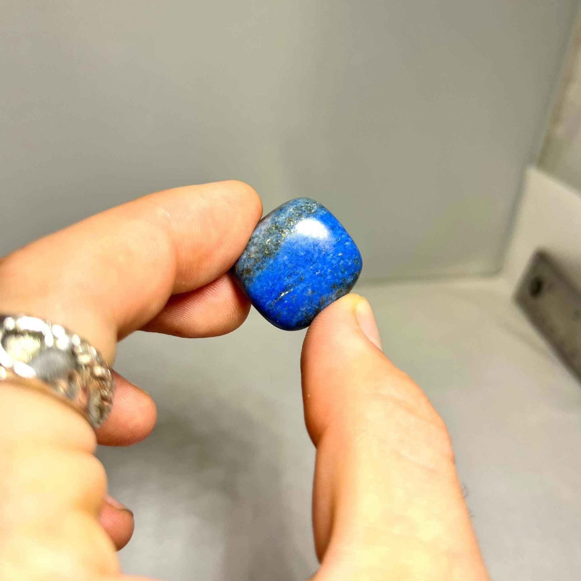 A tumbled lapis lazuli stone with natural gold and white mineral flecks.