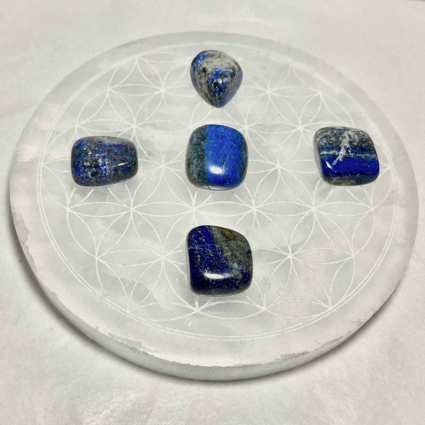 A smooth lapis lazuli pocket stone on a plain background.