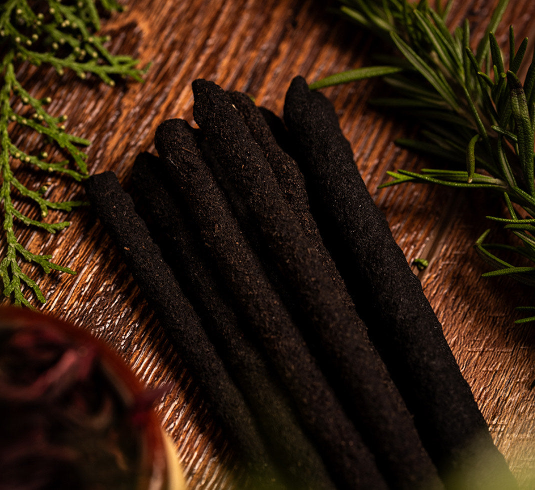 Close-up of the dark Manifest incense sticks on wood with rosemary