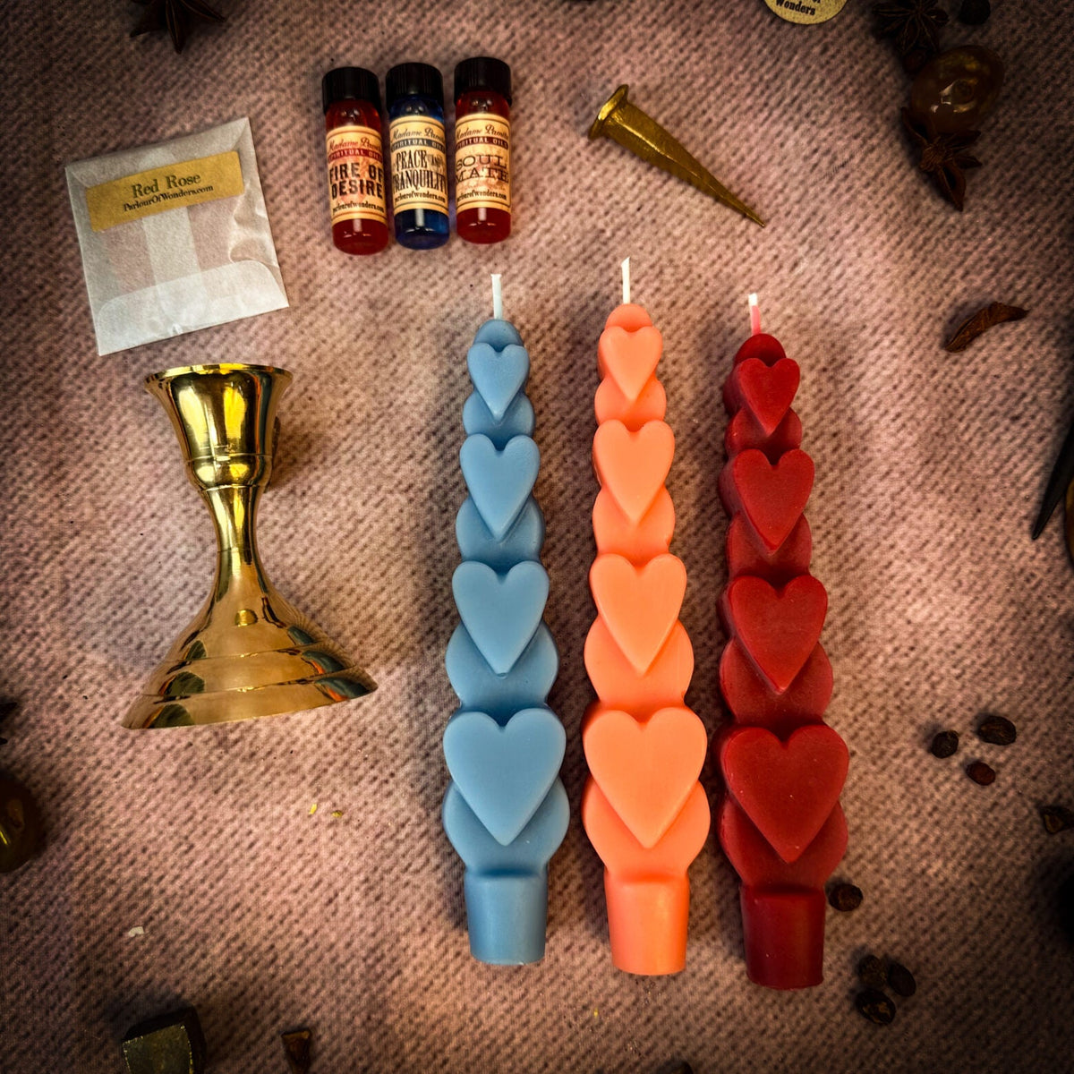 Blue, orange and red heart taper candles with three oil vials, a Red Rose herb sachet, the brass holder and a snuffer