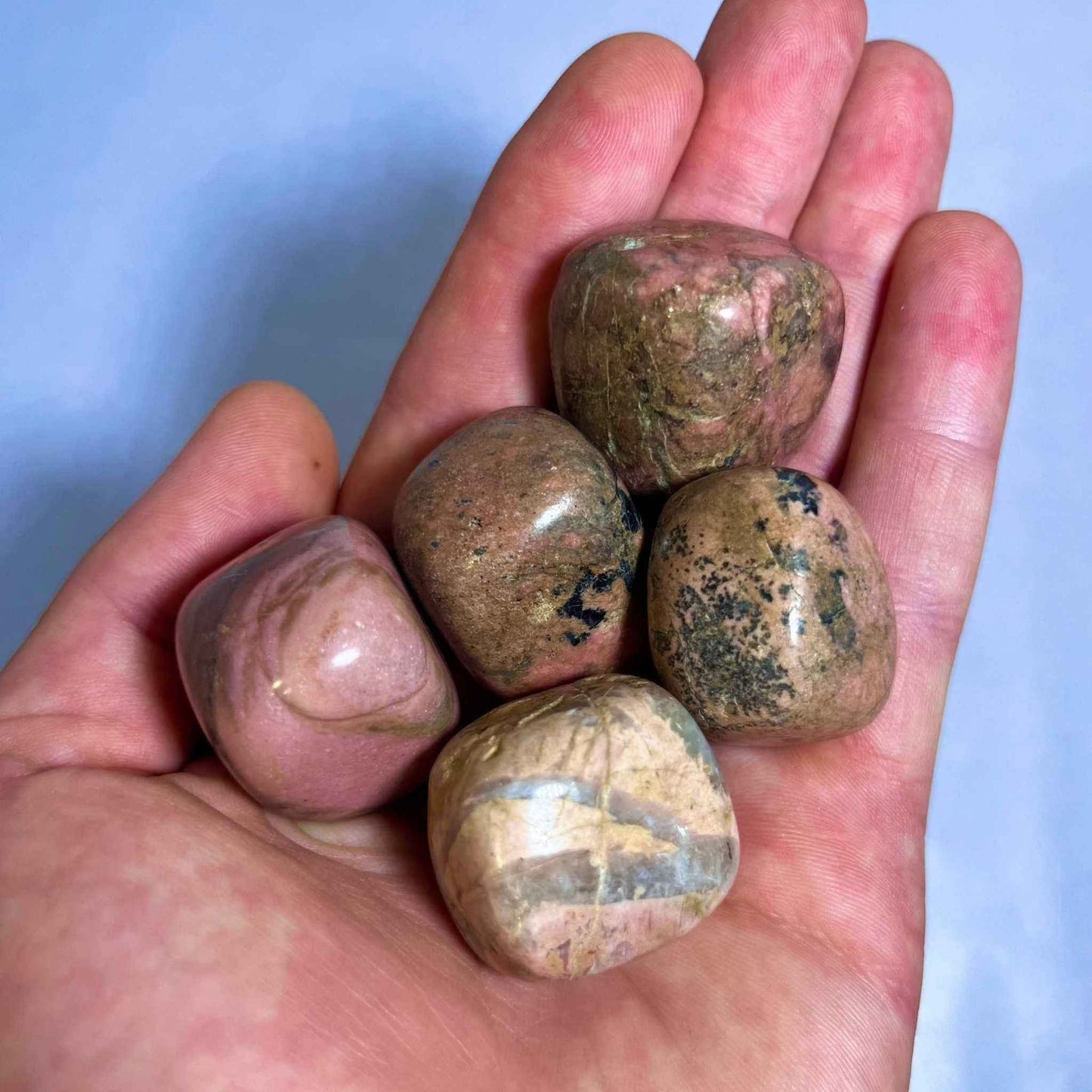 Close view of a rhodonite stone showing its pink and black patterning.