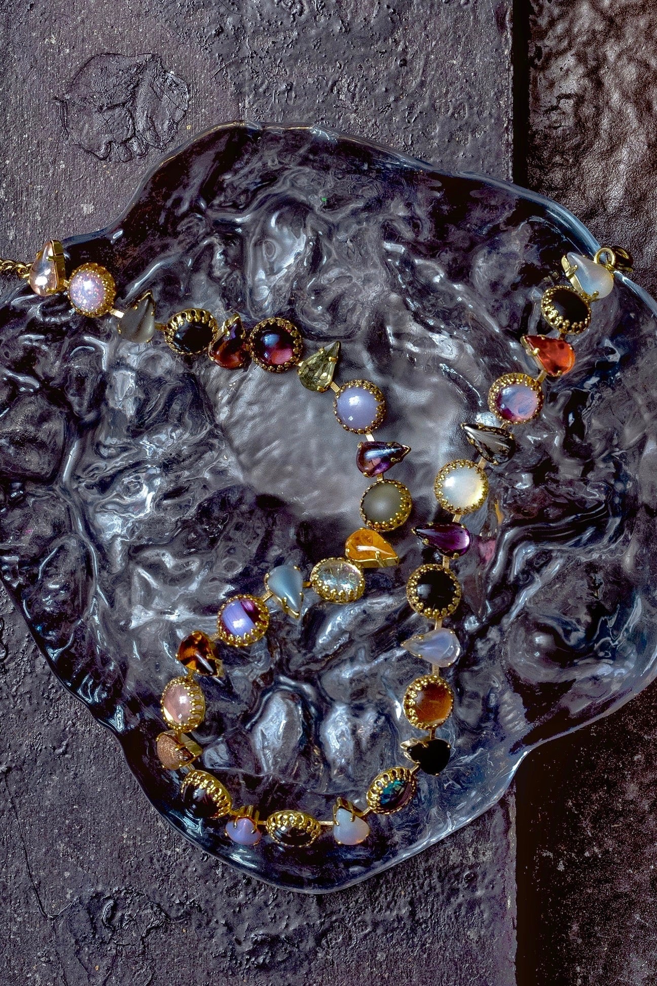 Detail of galaxy black, bruise purple and molten orange glass stones